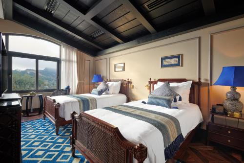 two beds in a room with a window at Silk Path Grand Sapa Resort & Spa in Sa Pa