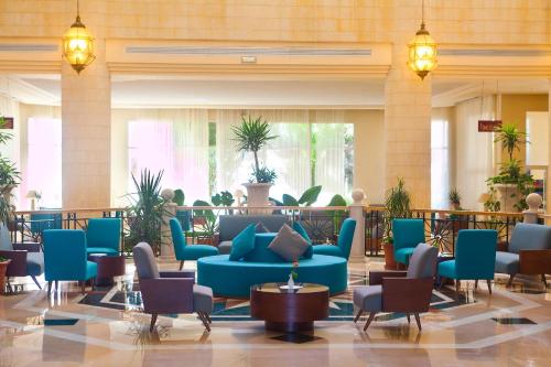 a lobby with blue couches and chairs and plants at El Mouradi Hammamet in Hammamet