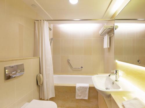 a bathroom with a tub and a sink and a toilet at The Salisbury - YMCA of Hong Kong in Hong Kong