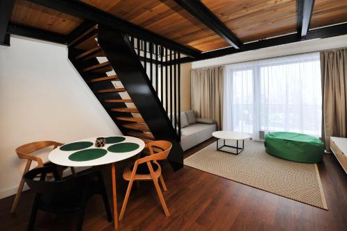a living room with a table and a spiral staircase at APLEND Vila Olívia in Vysoke Tatry - Novy Smokovec