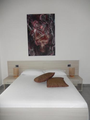 a white bed with two pillows and a painting above it at Il vecchio Fauno in Pompei