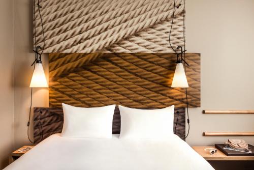 une chambre avec un lit avec deux oreillers blancs dans l'établissement ibis Saint Quentin en Yvelines - Vélodrome, à Montigny-le-Bretonneux