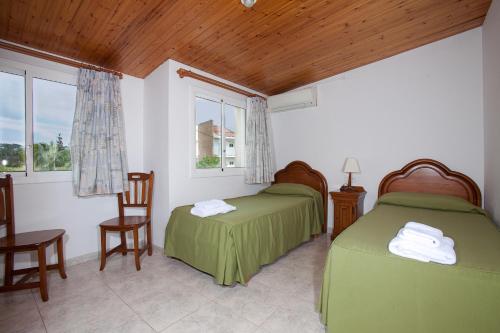 Habitación con 2 camas, 2 sillas y ventanas en Apartamentos Sunway Tara, en Sitges