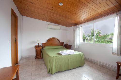 a bedroom with a bed with green sheets and a window at Apartamentos Sunway Tara in Sitges