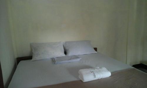 a white bed with two towels on top of it at Pedek Homestay in Praya