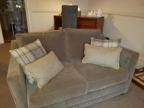 a brown couch with pillows on it in a living room at Ardshiel Hotel in Campbeltown