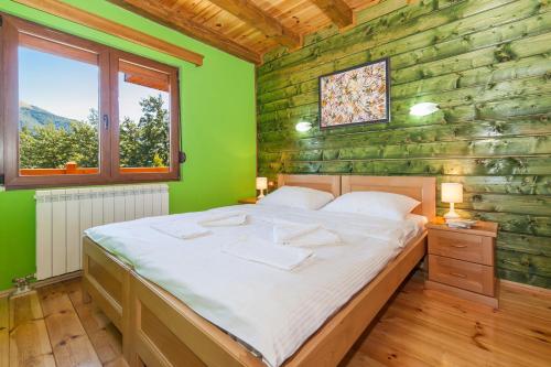 a bedroom with a bed and a green wall at Hotel & Resort Gacka in Mojkovac