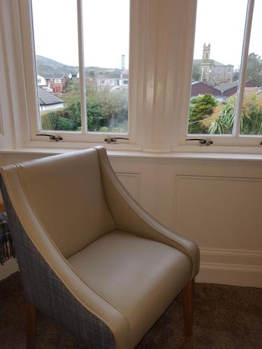 a chair sitting in a room with three windows at Ardshiel Hotel in Campbeltown
