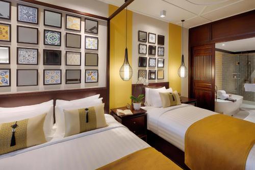 two beds in a hotel room with a bathroom at Allegro Hoi An . A Little Luxury Hotel & Spa in Hoi An