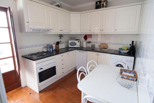 uma cozinha com armários brancos e uma mesa branca em Casa Barrela I em Tavira