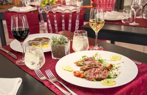 a table with two plates of food and glasses of wine at Hotel Grazia Eboli in Eboli
