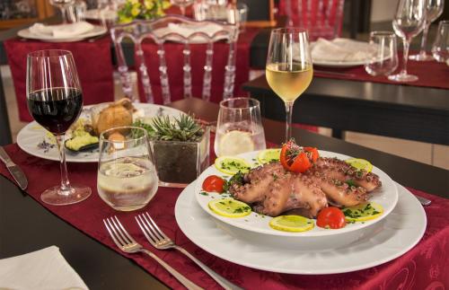 a table with a plate of food and glasses of wine at Hotel Grazia Eboli in Eboli