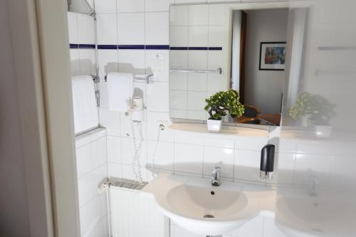 a white bathroom with a sink and a mirror at Hotel Condor in Hamburg