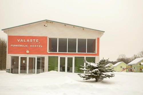 a building with a tree in the snow at Valaste Puhkeküla in Kohtla-Järve