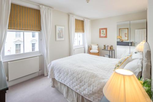 - une chambre avec un lit blanc et une grande fenêtre dans l'établissement Bright flat for 6, near Victoria and Warwick square, à Londres