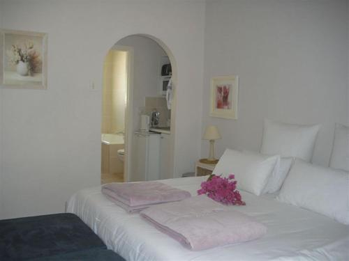a white bed with towels and a bouquet of flowers on it at Peak Village Lodge in Bloubergstrand