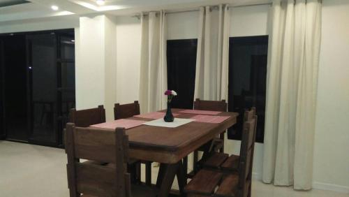 The Guest House Laoag في لواوْغ: طاولة غرفة الطعام مع إناء من الزهور عليها