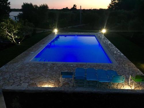 a swimming pool at night with chairs and lights at Trullo Grazioso Luxury in Ceglie Messapica