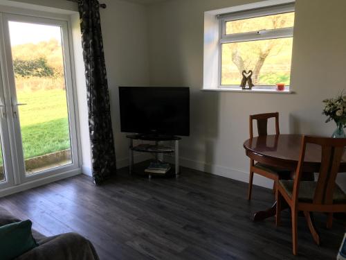 uma sala de estar com uma televisão, uma mesa e uma janela em The Annex, Fruit and Honey Farm em Bridgwater