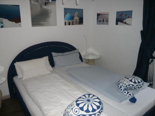 a bed with white sheets and blue and white pillows at Pension am Weinberg in Mesenich