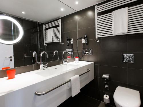 a bathroom with two sinks and a mirror at DORMERO Hotel Hannover in Hannover