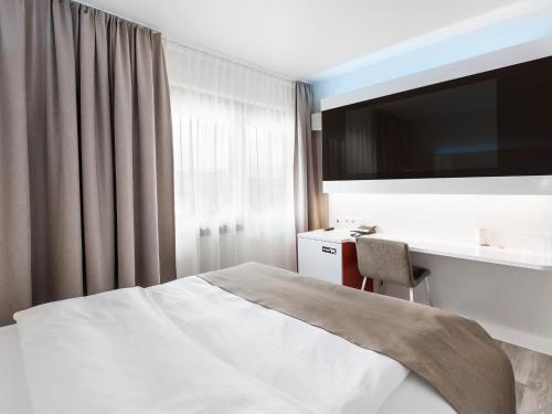 a hotel room with a bed and a desk and a television at DORMERO Hotel Hannover in Hannover