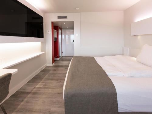 a hotel room with a bed and a flat screen tv at DORMERO Hotel Hannover in Hannover
