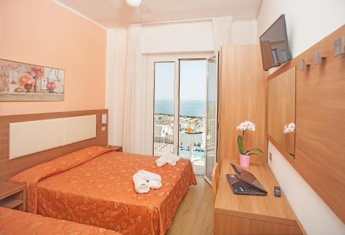 a bedroom with a bed and a desk and a window at Hotel Sara in Rimini