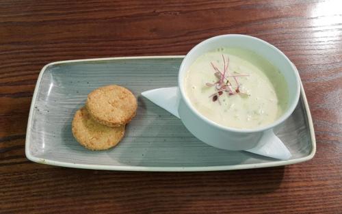 a plate with a cup of soup and a biscuit at Cove Bay Hotel in Aberdeen