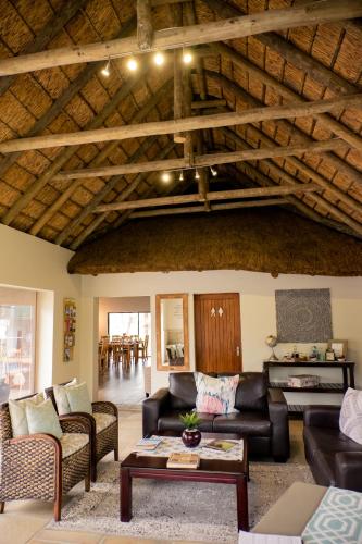 a living room with leather furniture and a wooden ceiling at De Old Drift Guest Farm in Addo