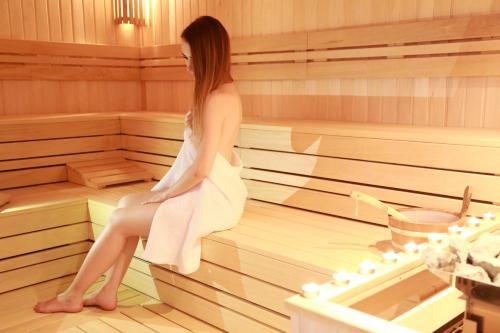 a woman is sitting in a sauna at Hotel Opal Superior - Adults Only in Gyöngyös