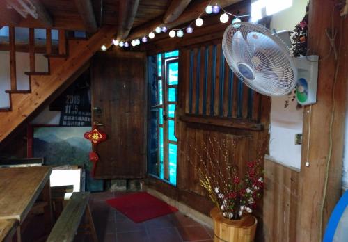 a room with a fan and a table and stairs at Matsu 1st Hostel in Nangan