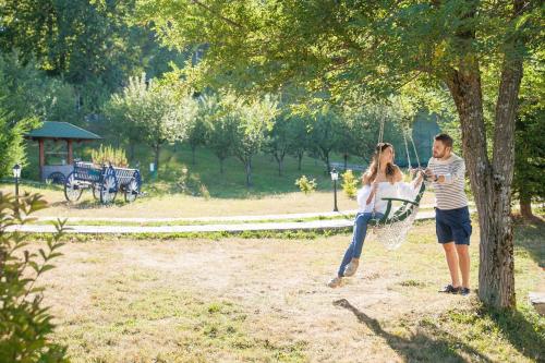 a man and a woman standing under a tree at Hotel & Resort Gacka in Mojkovac