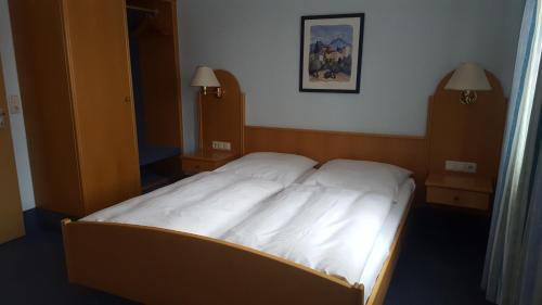 a bedroom with a white bed with two night stands at Gasthaus Krone in Wiesentheid