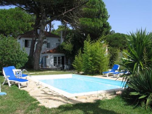 a swimming pool with two blue chairs and a house at Casa Turquesa in Sintra