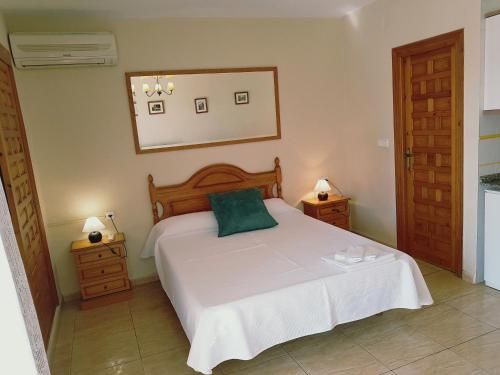 a bedroom with a bed with a green pillow on it at Apartamentos Olympia Garden in La Manga del Mar Menor