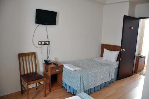 a bedroom with a bed and a chair and a television at Hekimoğlu Hotel in Erzurum