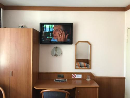 a room with a tv on the wall with a desk at Miles Hotel Berlin in Berlin