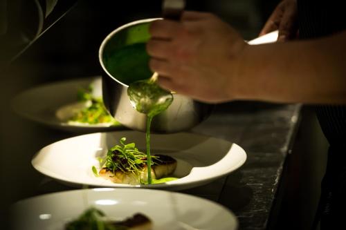 a person is pouring food into plates of food at Auberge du Raisin in Cully