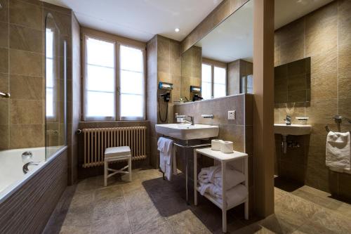 Auberge du Raisin في كولي: حمام مع حوض ومغسلة وحوض استحمام