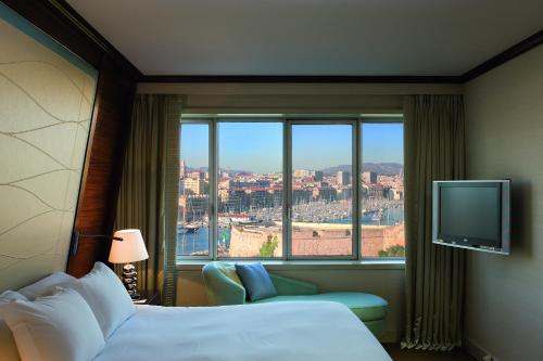 a hotel room with a bed and a large window at Sofitel Marseille Vieux-Port in Marseille