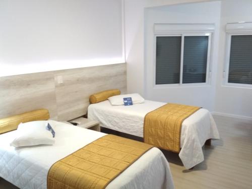 a hotel room with two beds and two windows at Hotel Solaris in São Miguel dʼOeste