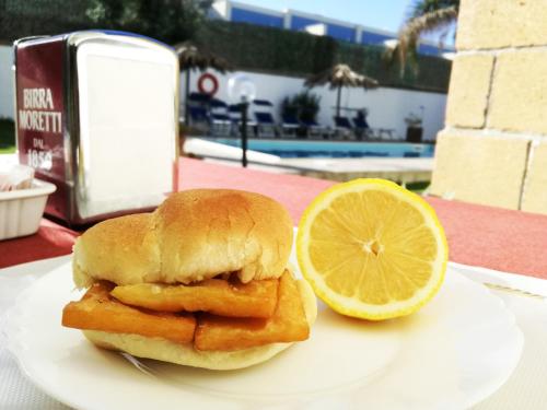 a fish sandwich with a slice of lemon on a plate at Brunelli Residence in Mazara del Vallo