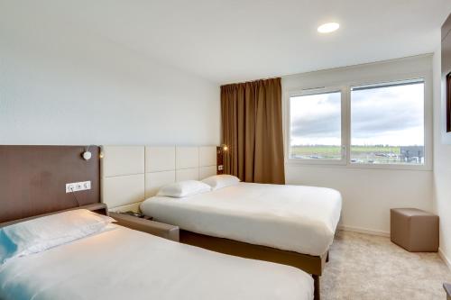 a hotel room with two beds and a window at The Originals City, Hôtel Caen Mémorial in Caen