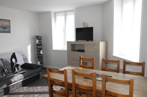 een woonkamer met een tafel en stoelen en een televisie bij Location La mouette in Fort-Mahon-Plage