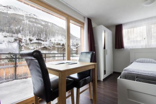 a room with a desk and a bed and a window at Apartment Dorfblick in Saas-Fee