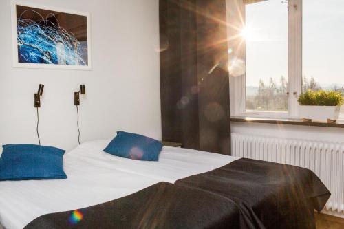 a bedroom with a bed with blue pillows and a window at Sundsgården hotell & konferens in Helsingborg
