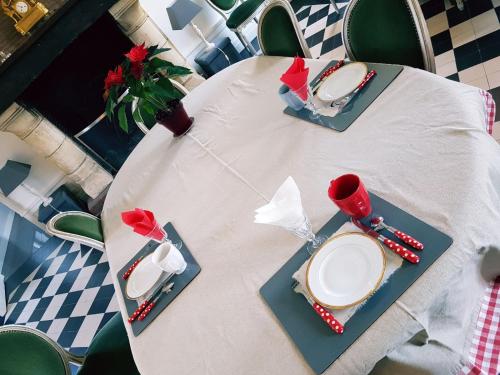 a table with red and white plates on it at Manoir de l'As de Trèfle in Isneauville