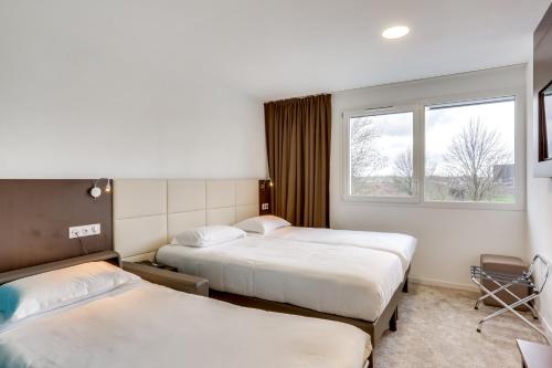 a hotel room with two beds and a window at Inspiration by balladins Caen Mémorial in Caen