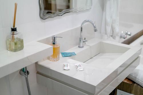 uma casa de banho branca com um lavatório e um espelho em Hotel Almanara em Pirapozinho